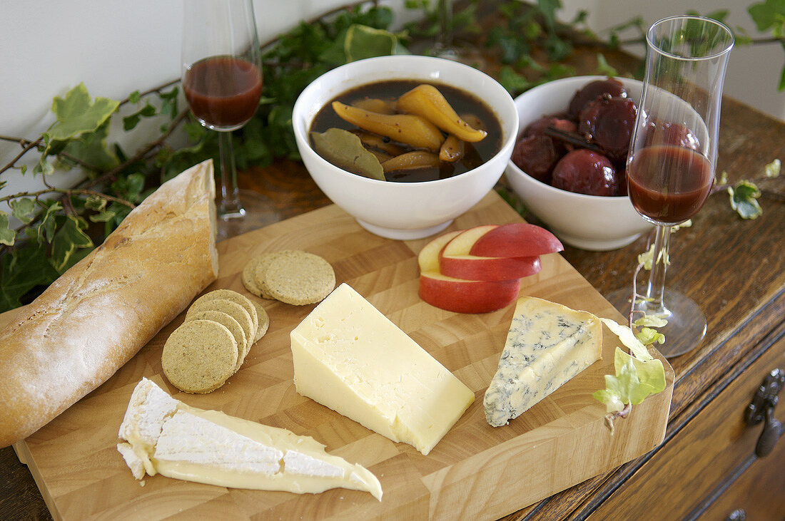 Cheese on a wooden board, pickled fruit and baguette
