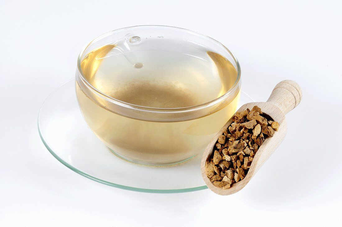 Cup of tea with dried Atractylodes root in scoop
