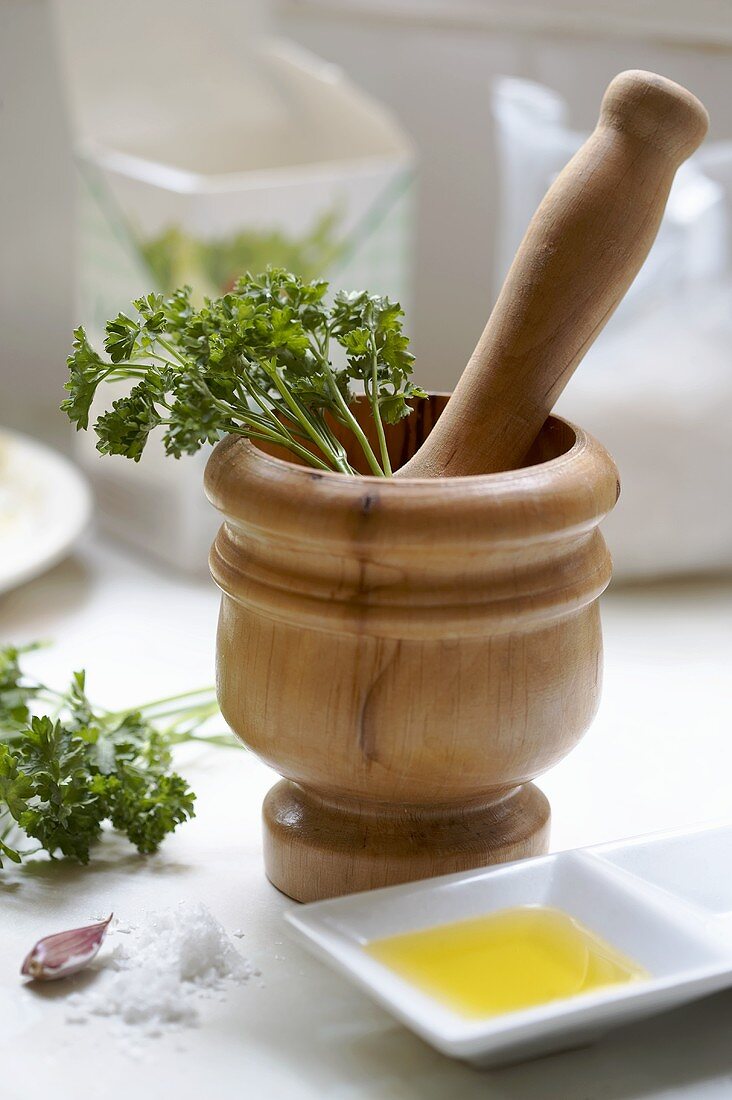Wooden pestle & mortar with ingredients for parsley pesto