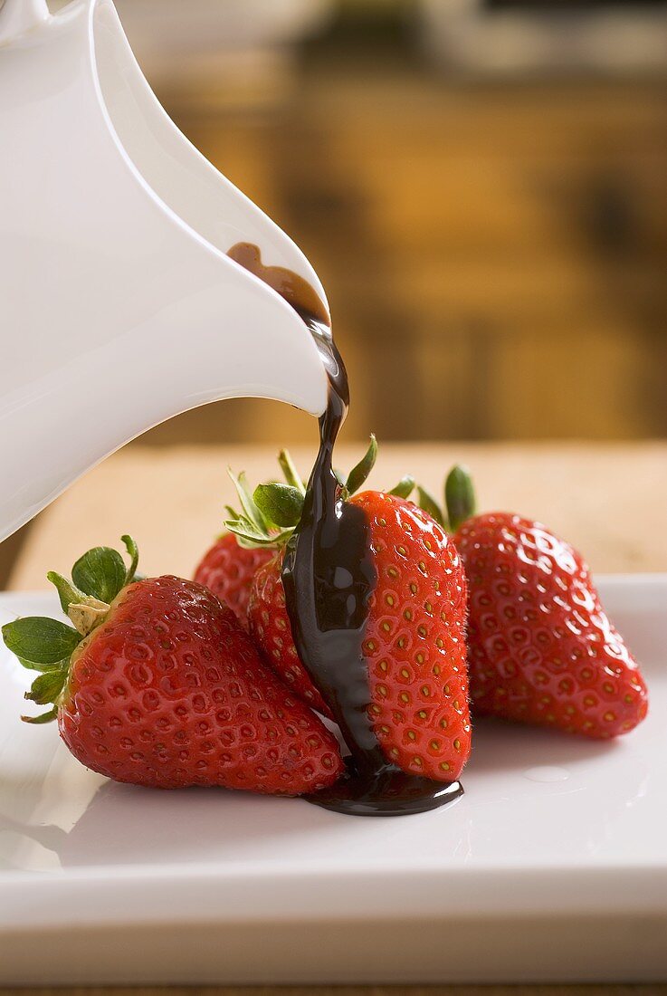 Pouring chocolate sauce over fresh strawberries