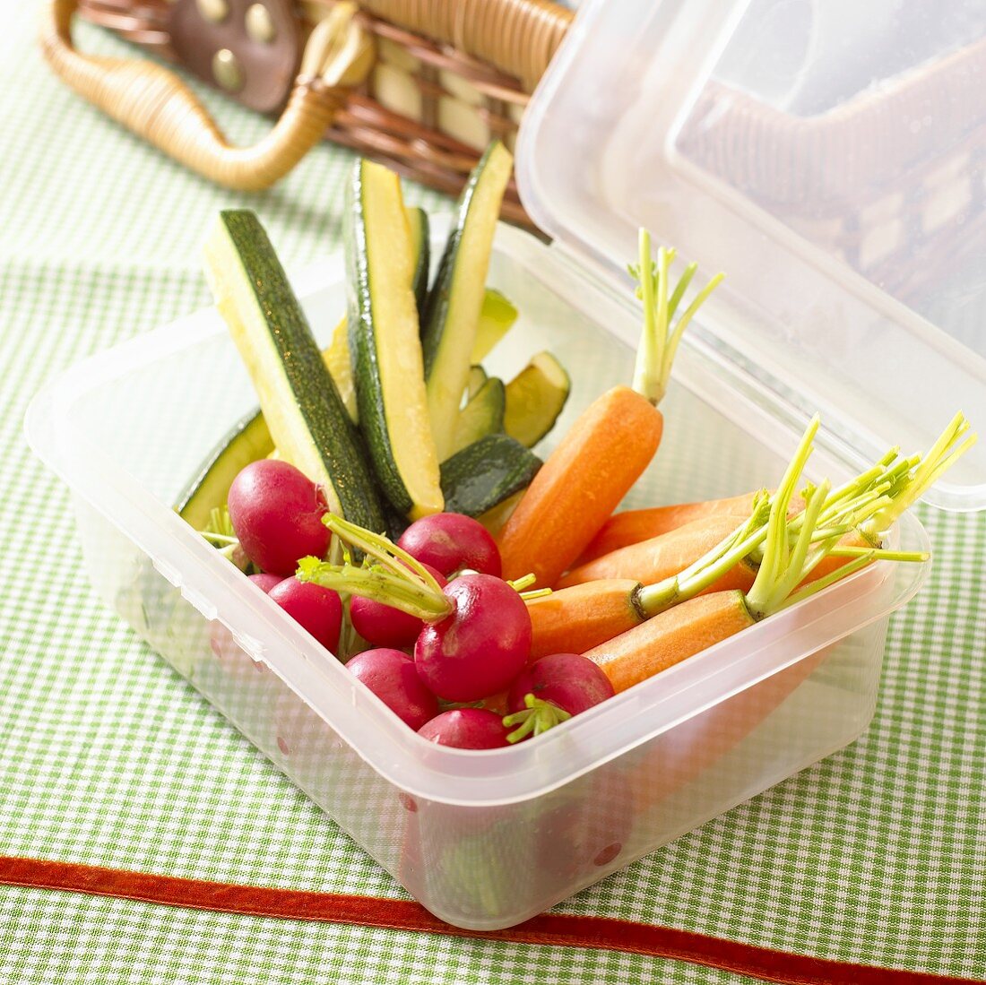 Carrots, radishes and courgettes in a plastic box