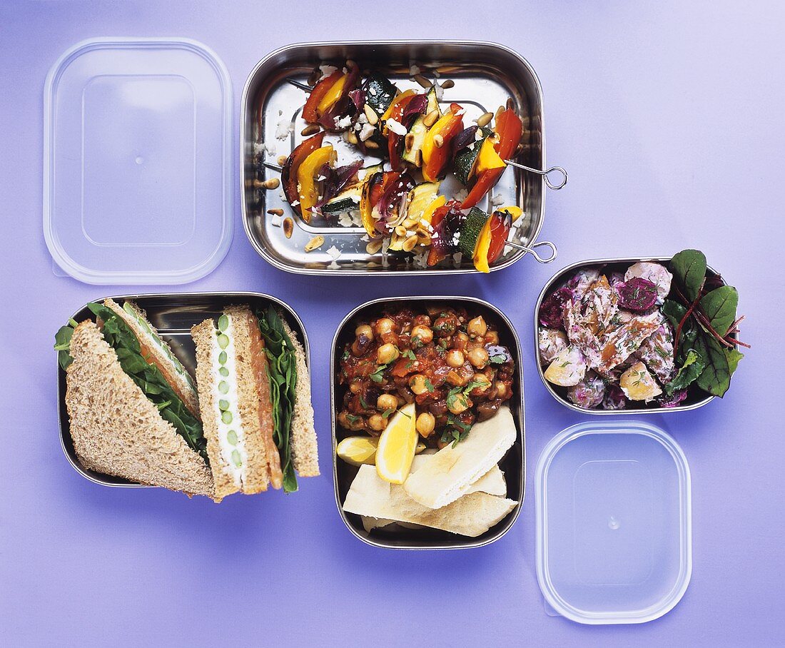 Salads, vegetable kebabs and sandwiches in lunch boxes