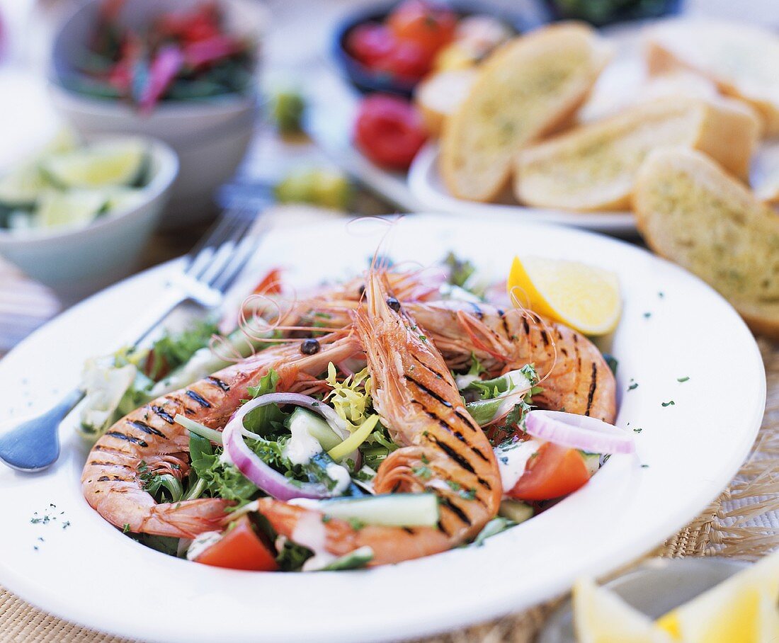 Grilled prawns on summer salad with herb baguette