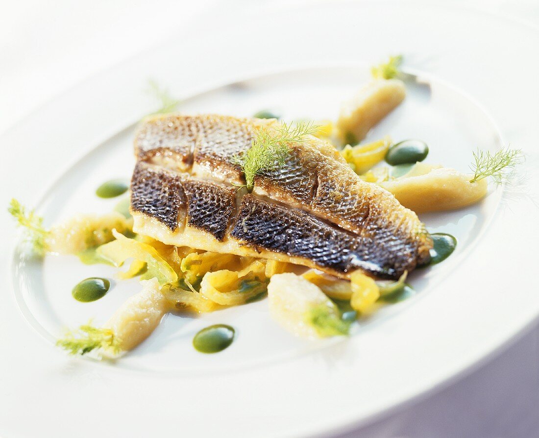 Fried sea bass on vegetables with pesto