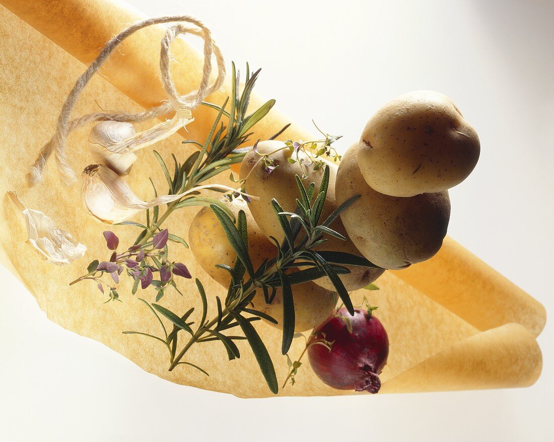 Kartoffeln mit Kräutern, Zwiebel und Knoblauch auf Backpapier