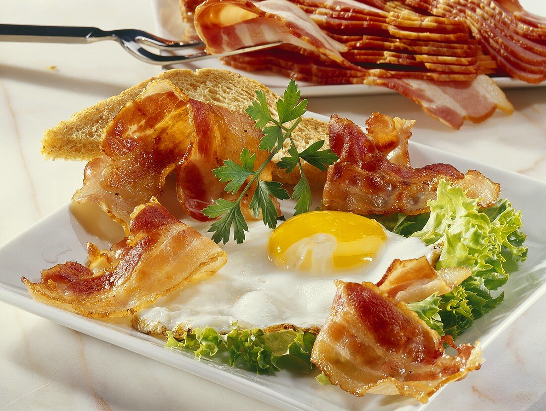 Fried egg and bacon with toast on lettuce leaf