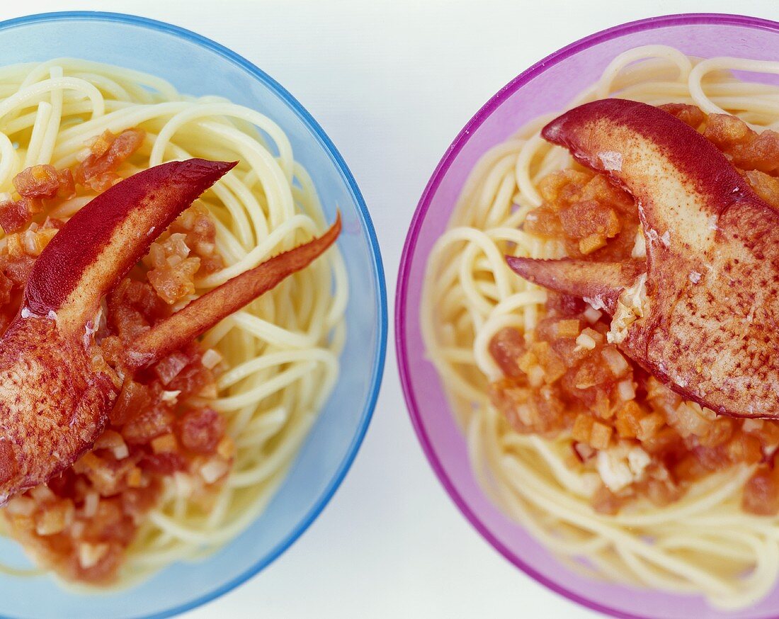 Two plates of spaghetti with tomato sauce and lobster