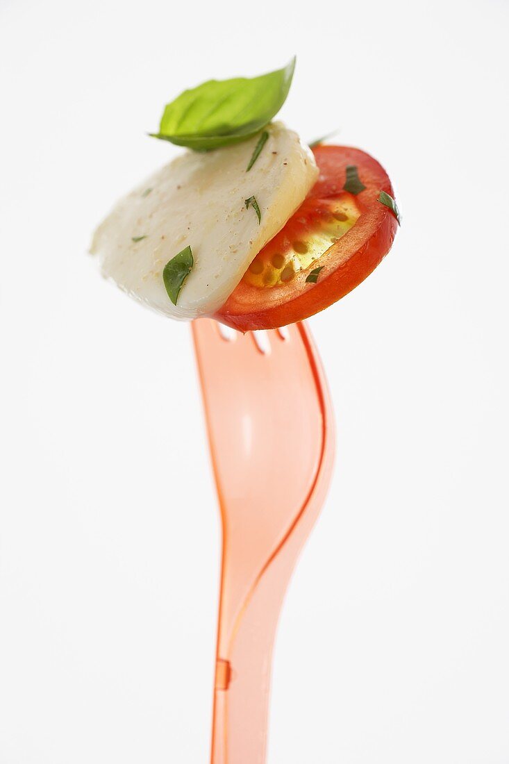 Tomate mit Mozzarella und Basilikum auf Plastikgabel