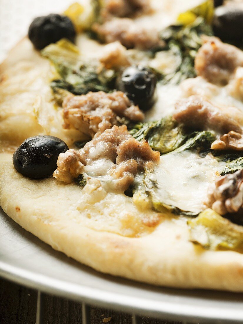 Pizza with mince, olives, spinach and cheese (close-up)