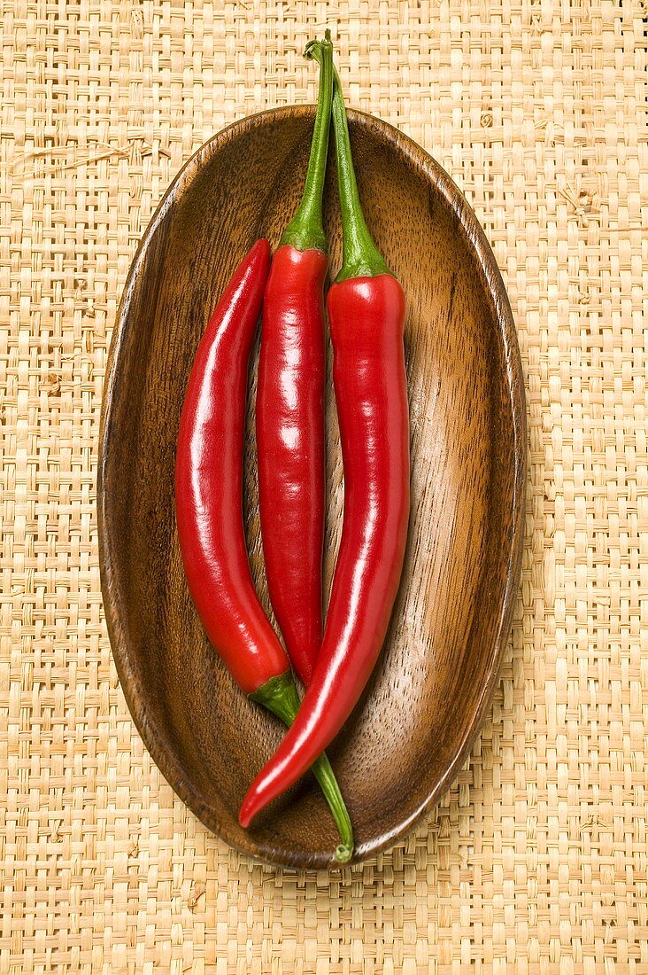 Three chili peppers in wooden bowl