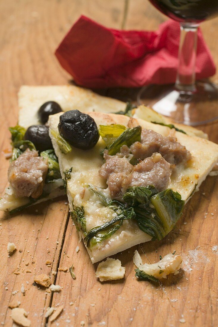 Two slices of pizza with tuna, chard and olives