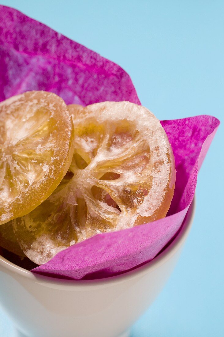 Candied lemon slices in bowl with purple paper