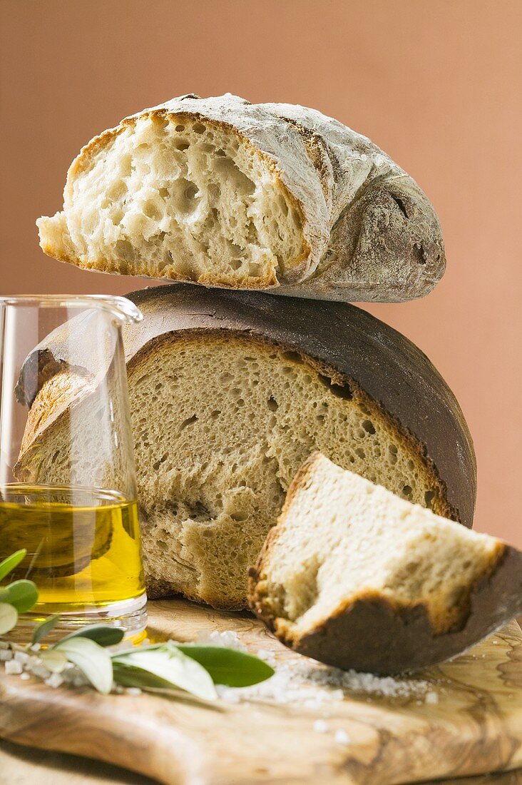 Rustic bread, two loaves with pieces cut off, olive oil, salt