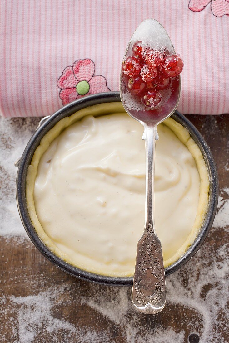 Baking tin with pastry & vanilla cream, redcurrants on spoon