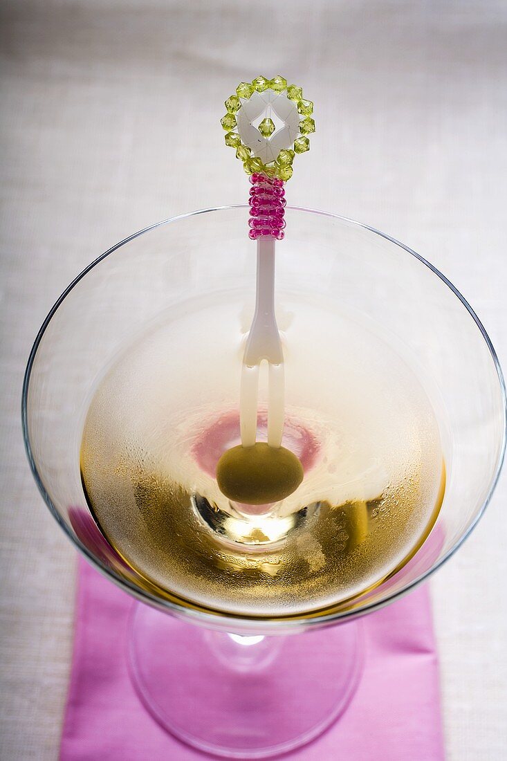 Martini mit grüner Olive auf Cocktailgabel