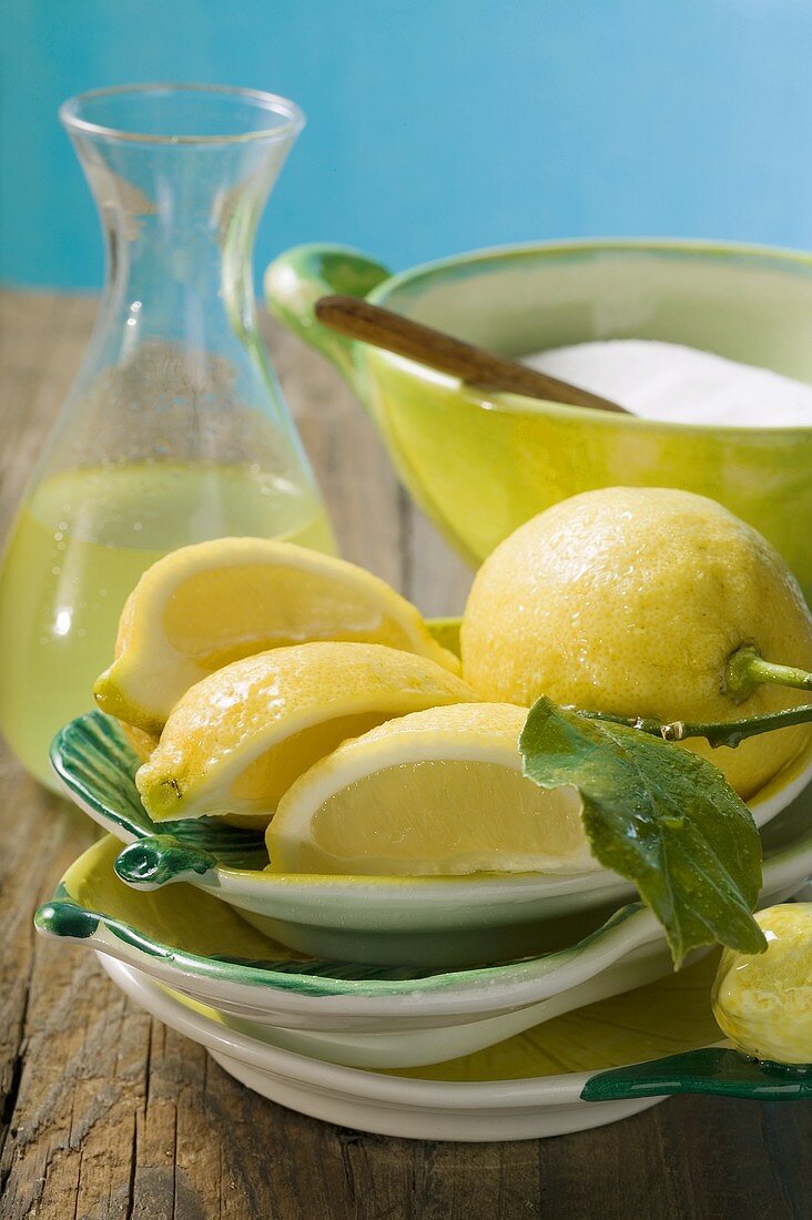 Frische Zitronen mit Blättern, Zitronensaft und Zucker