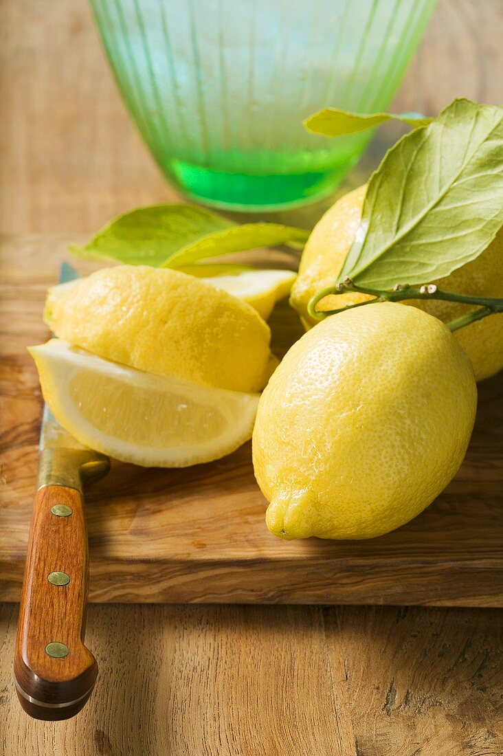 Frische Zitronen mit Blättern vor Wasserkrug