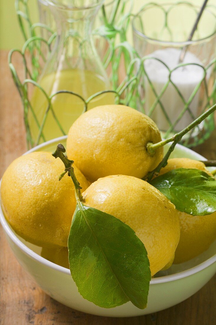 Fresh lemons with leaves in bowl, lemon juice, sugar