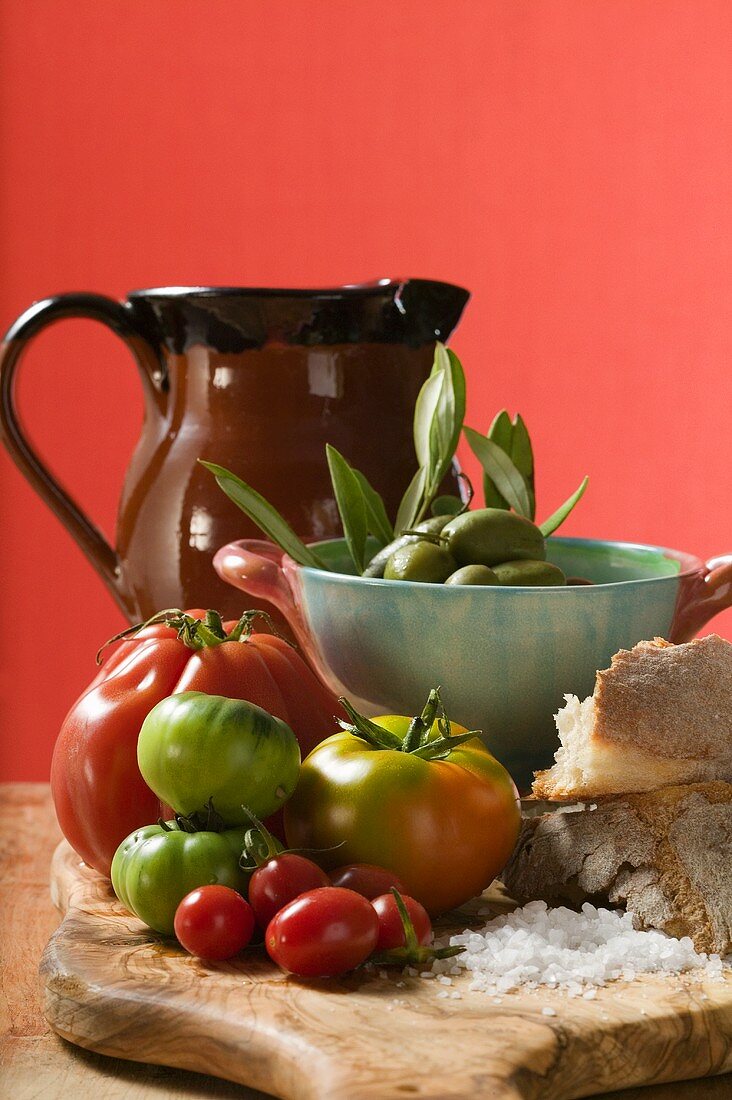 Frische Tomaten, Oliven, Brot, Salz und Tonkrug
