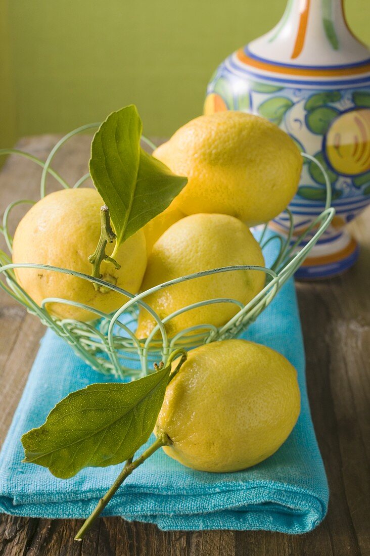 Fresh lemons with leaves in wire basket