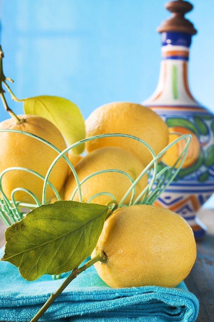 Fresh lemons with leaves in wire basket