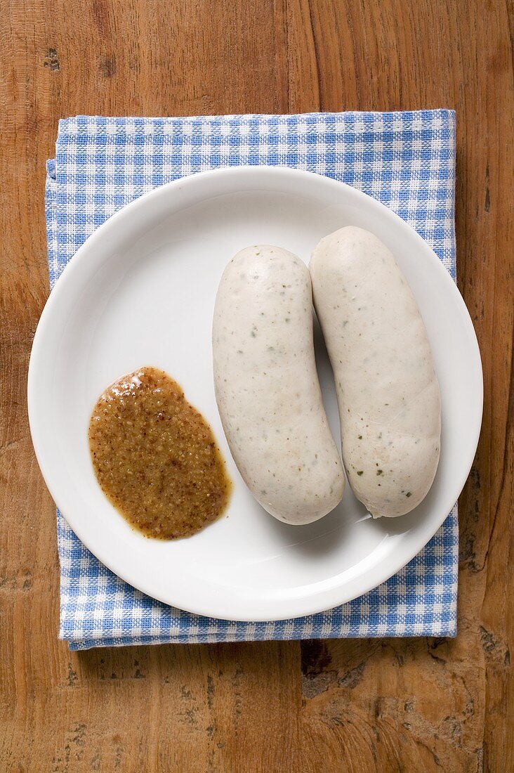 Zwei gekochte Weisswürste mit Senf auf Teller