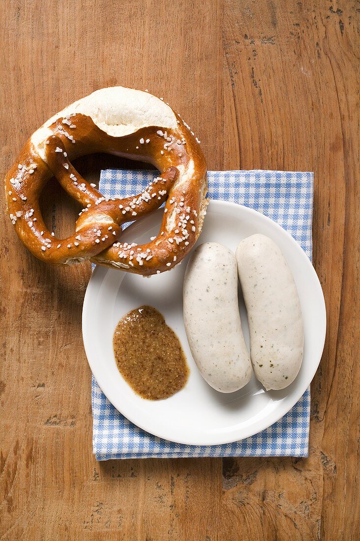 Zwei gekochte Weisswürste mit Senf und Brezel auf Teller