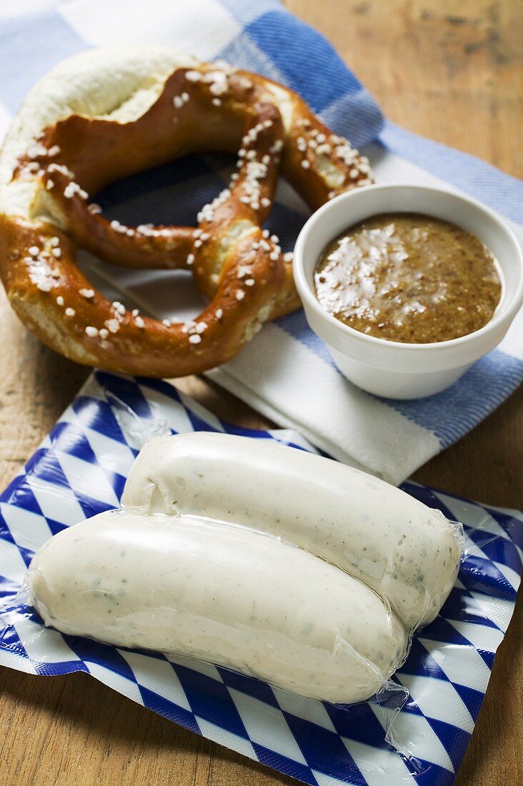 Two Weisswurst in packaging, pretzel and mustard