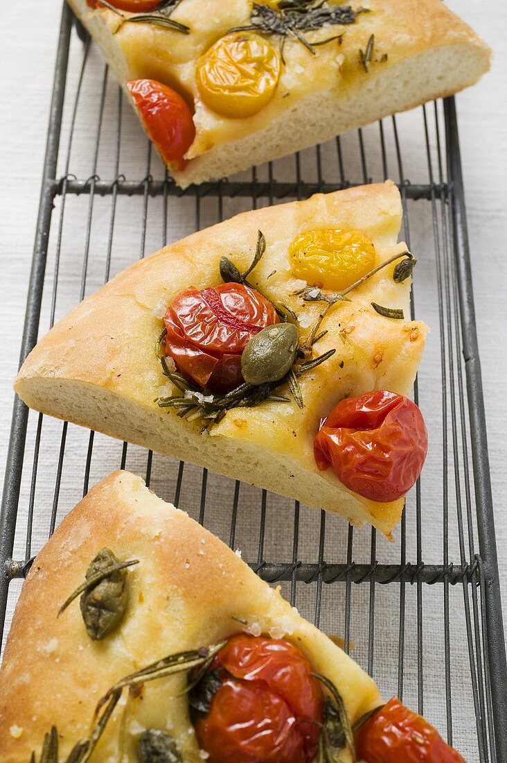 Three slices of pizza with cherry tomatoes, capers & rosemary