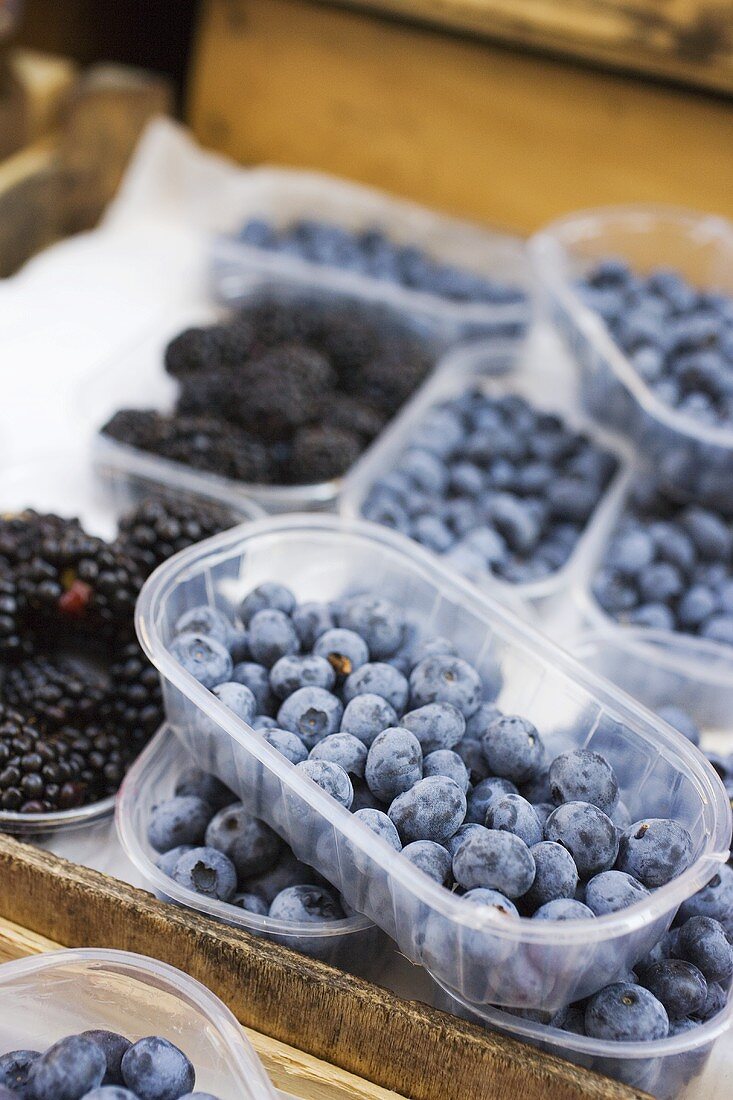 Blueberries & blackberries in plastic punnets at a market