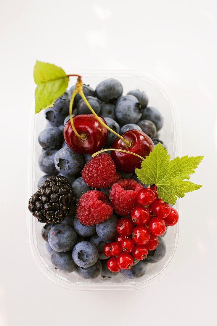 Assorted berries and two cherries in plastic punnet