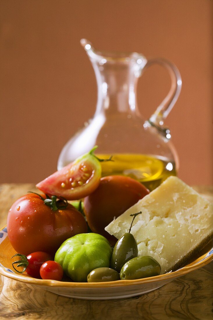 Tomaten, grüne Oliven und Parmesan auf Teller, Olivenöl