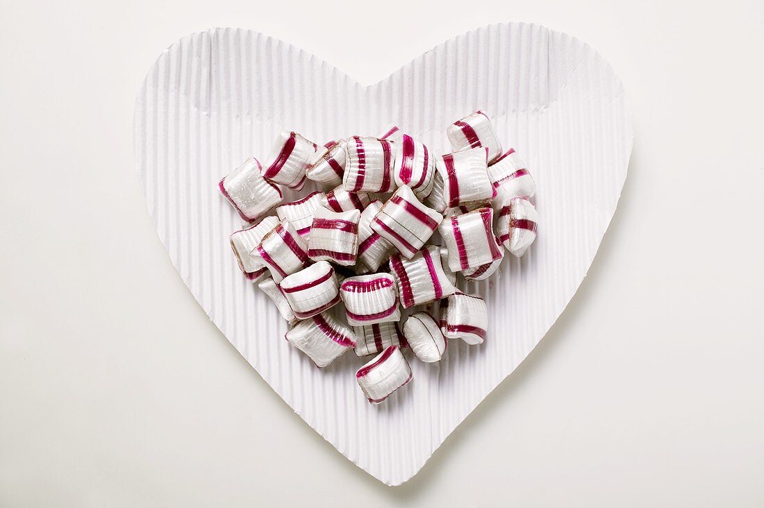 Cherry mint sweets on heart-shaped paper plate