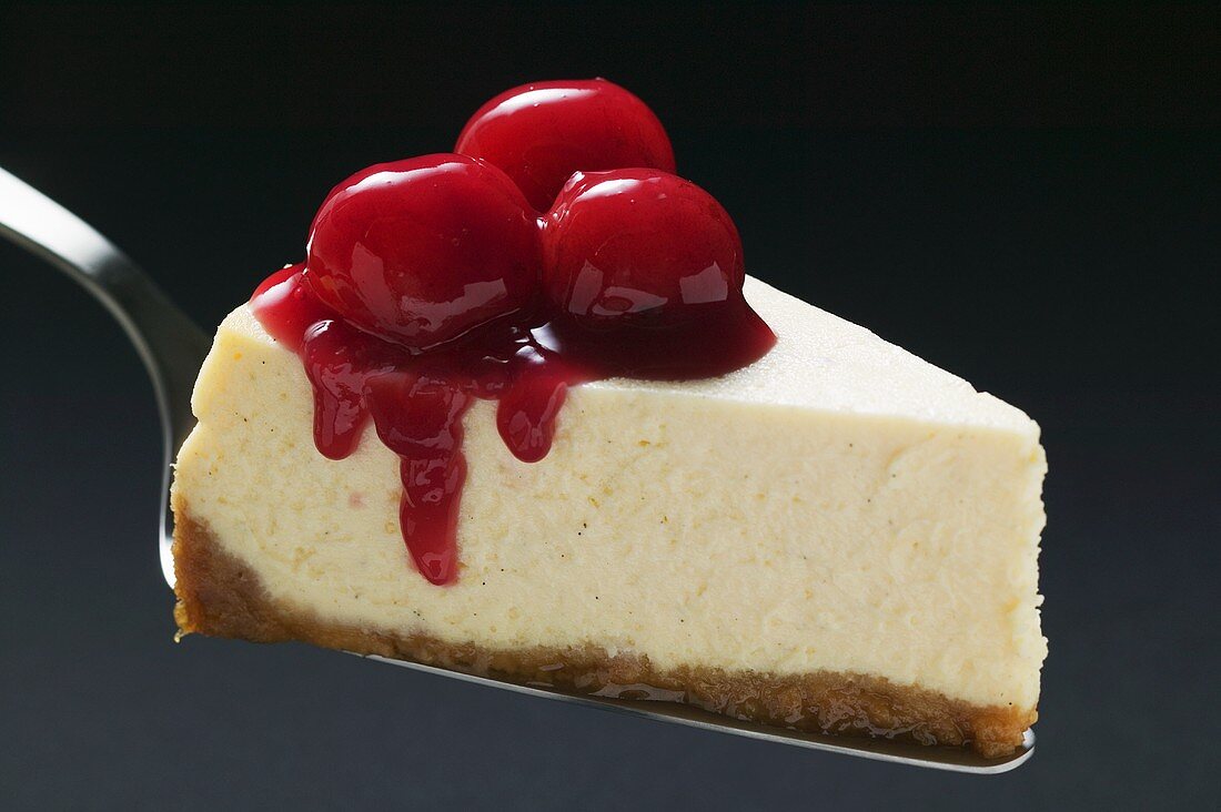 Slice of cheesecake with cherries on cake server