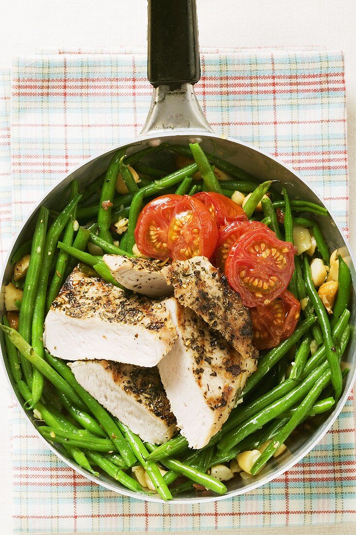 Chicken breast with green beans and tomatoes in frying pan