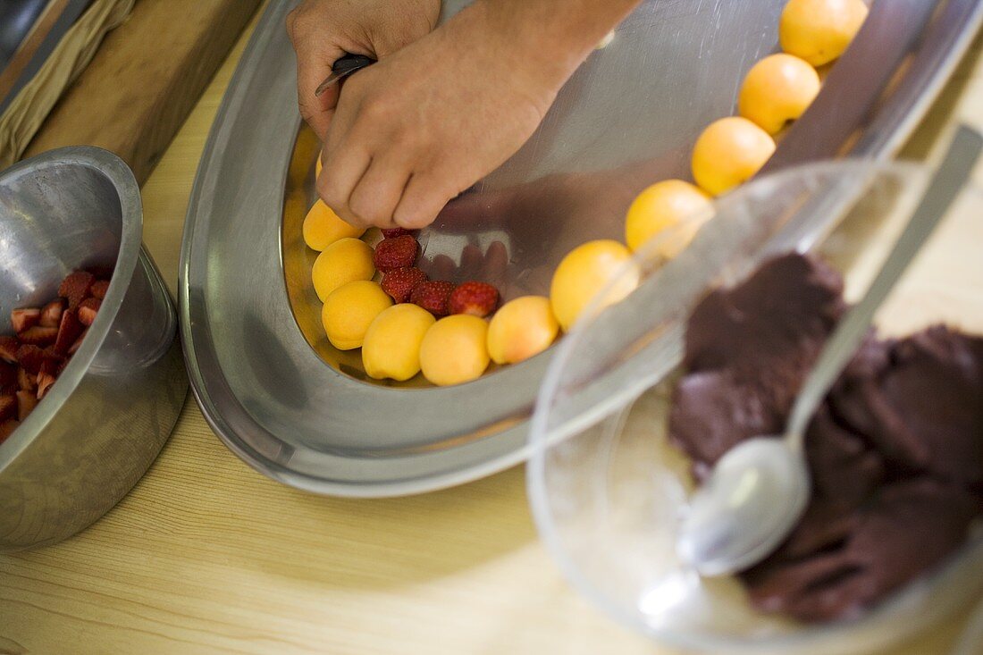 Erdbeeren neben Aprikosen auf Platte legen