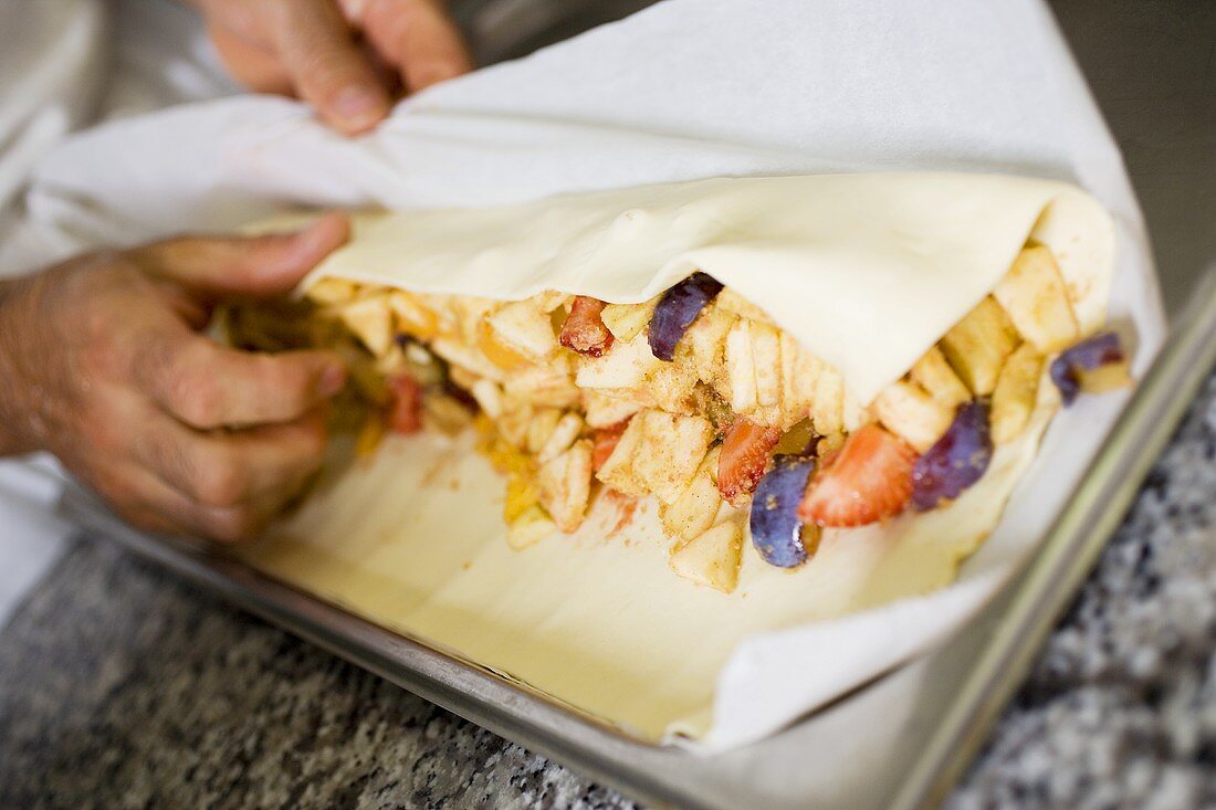 Making fruit strudel: rolling up the strudel