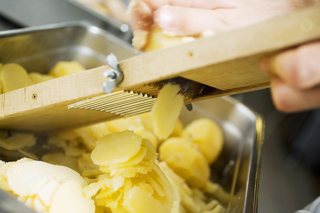 Gekochte Kartoffeln mit Reibe in Scheiben schneiden