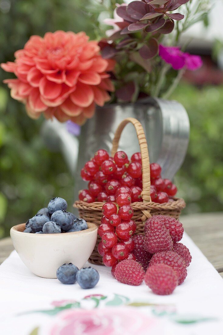 Frische Beeren und Blumenstrauss auf rustikalem Tisch