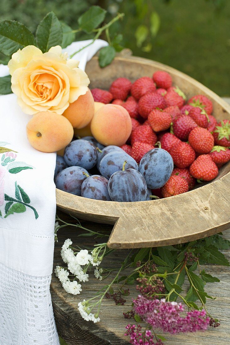 Pflaumen, Erdbeeren und Aprikosen in Holzschale