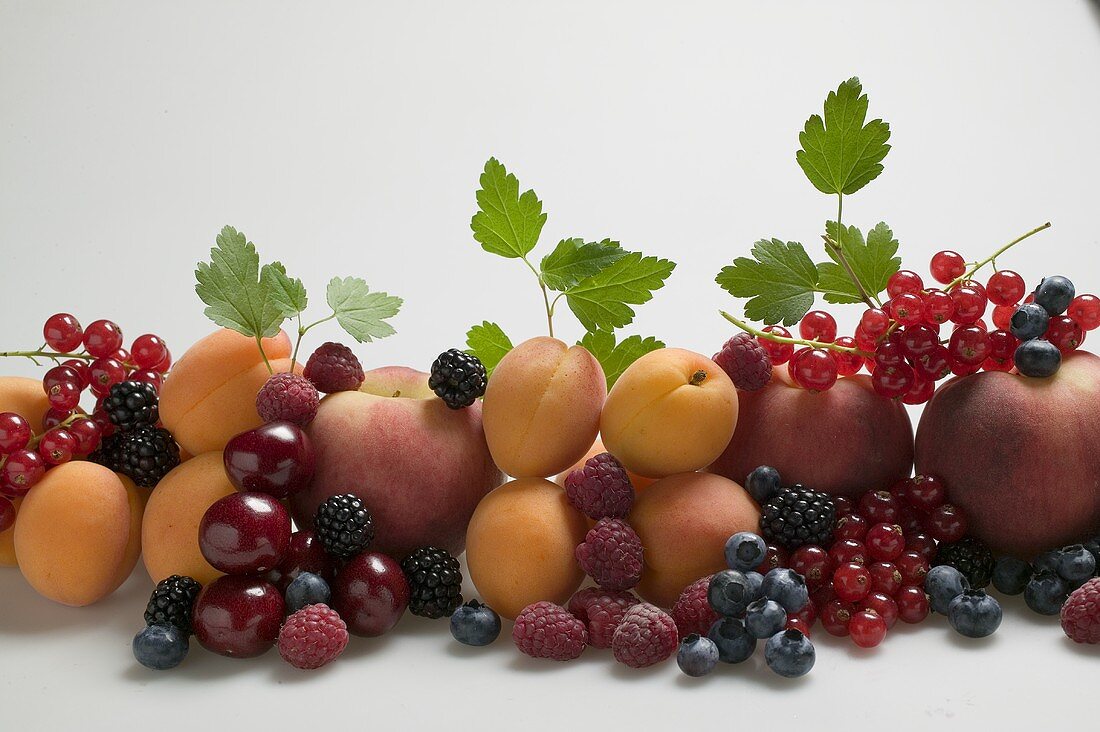 Fruit still life with stone-fruit, berries and leaves