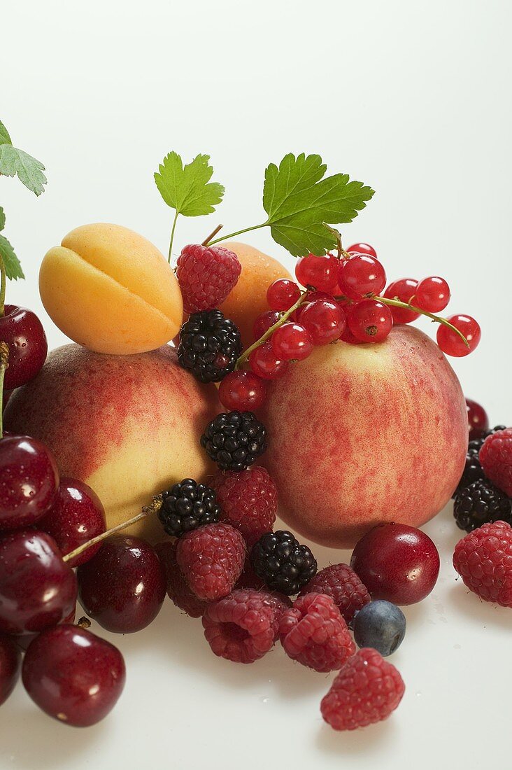 Obststillleben mit Steinobst, Beeren und Blättern