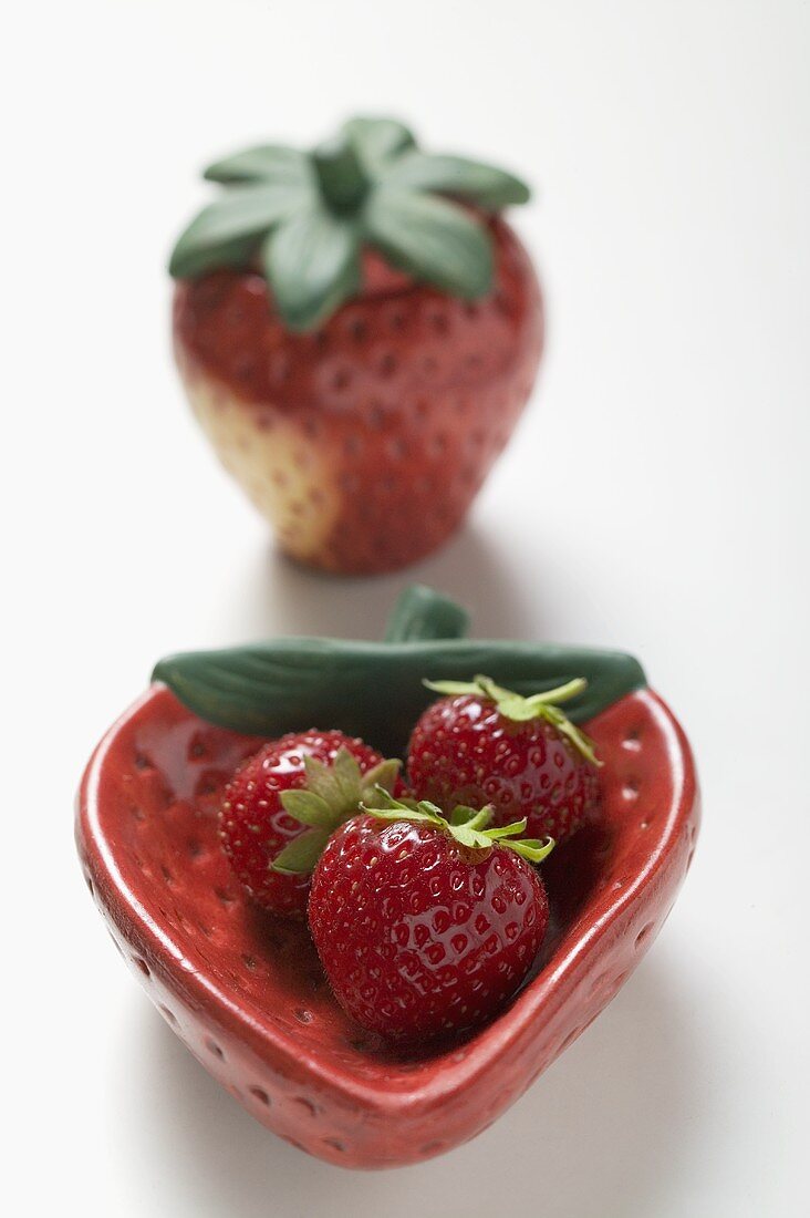 Three strawberries in red strawberry-shaped dish
