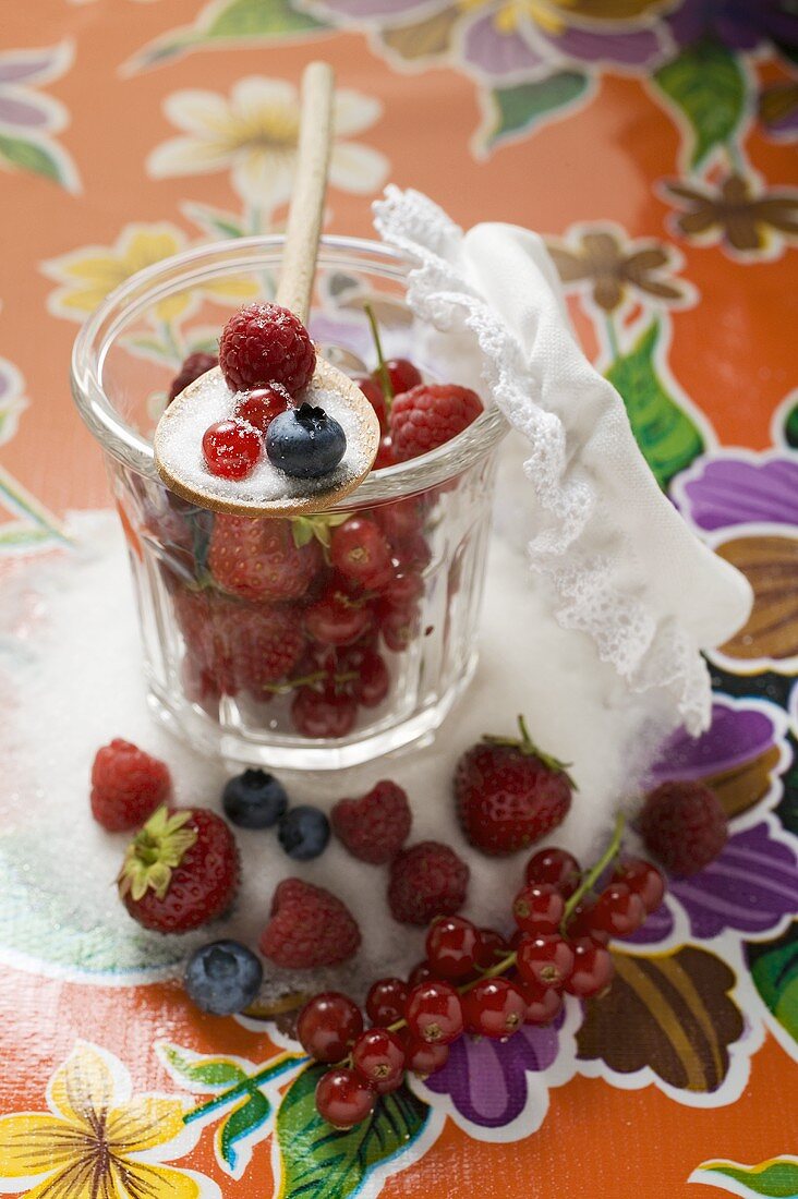 Frische Beeren im Marmeladenglas mit Zucker und Kochlöffel