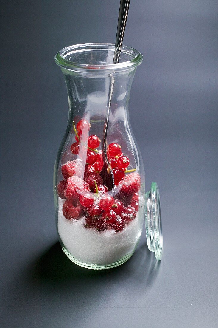 Fresh berries with sugar in carafe with spoon