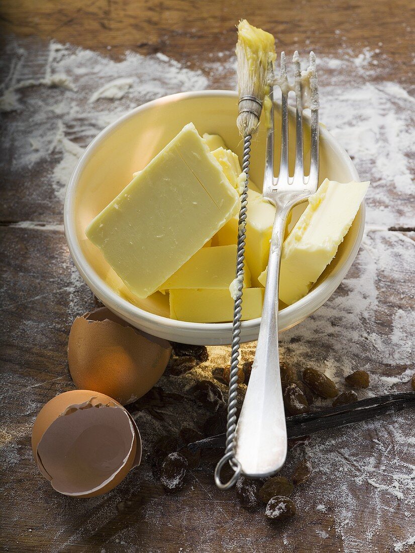 Verschiedene Backzutaten (Butter, Eier), Backpinsel, Gabel