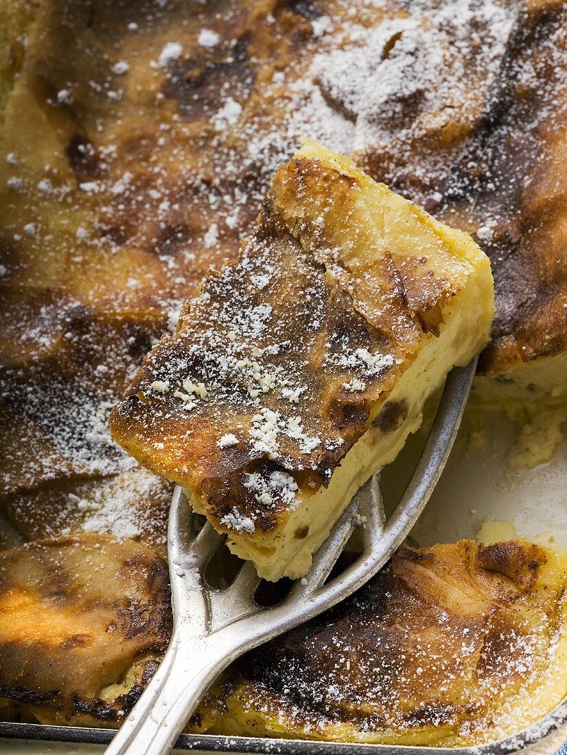 Curd cheese strudel in baking tin with piece on server