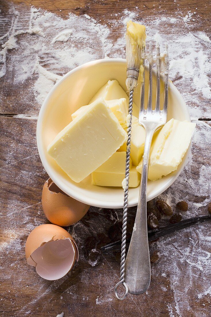 Butter im Schälchen, Eierschalen, Backpinsel und Gabel
