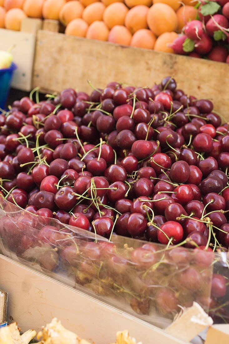 A heap of cherries in a crate at a market