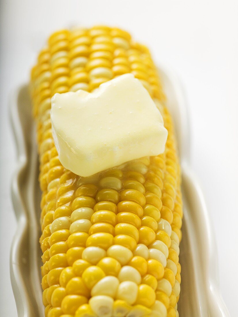 Maiskolben mit Stück schmelzender Butter